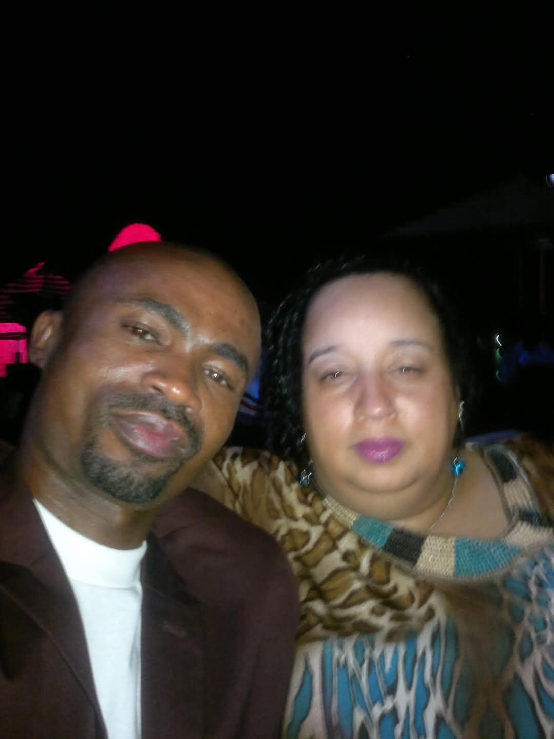 Man and woman posing together at night.