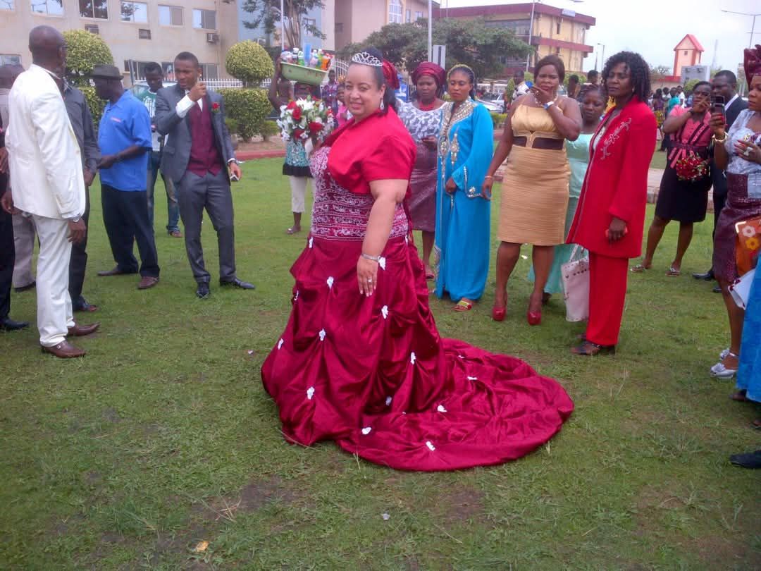 Bride in red gown surrounded by guests.